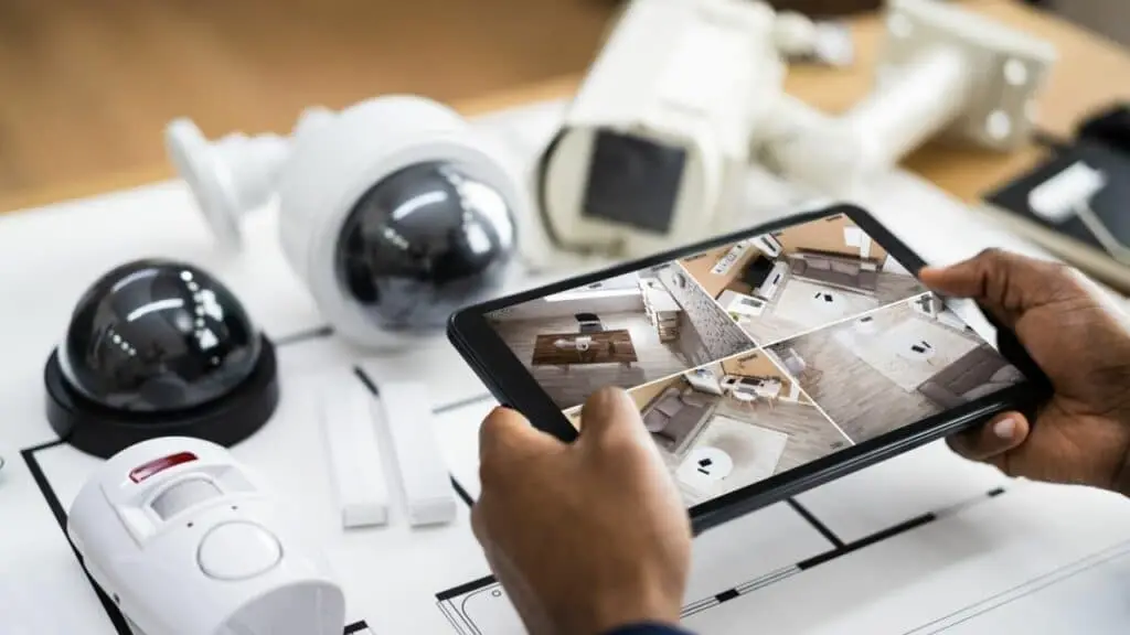 Person using a tablet to monitor CCTV security cameras with alarm and surveillance equipment